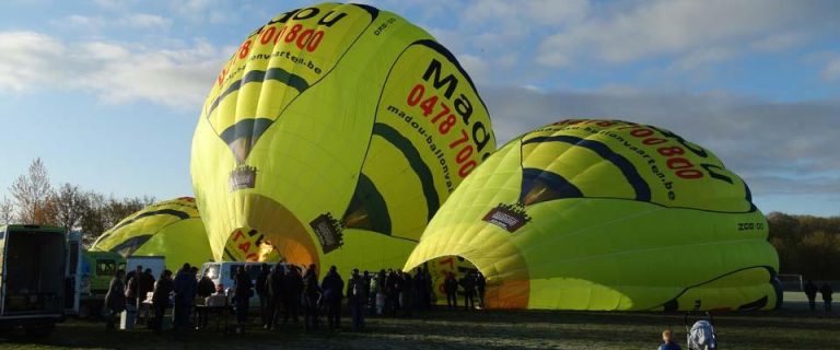 Ons team Warmeluchtballon stijgt op tijdens ochtendballonvaart in Oost-Vlaanderen met uitzicht over landschap