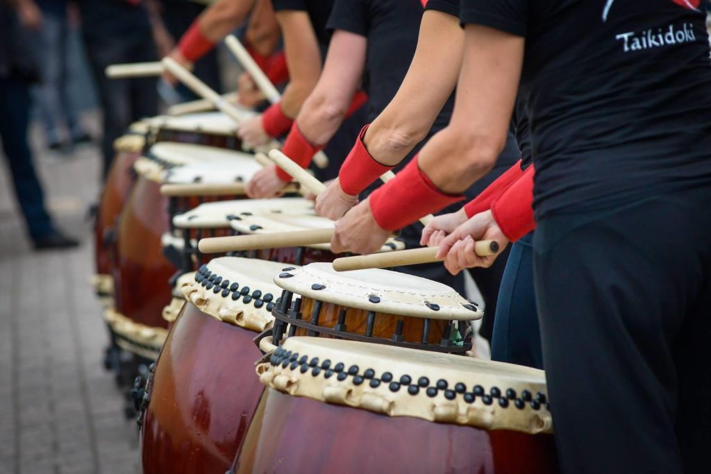 Groep deelnemers speelt Taiko drums samen tijdens een trainingssessie bij Araumi Daiko.